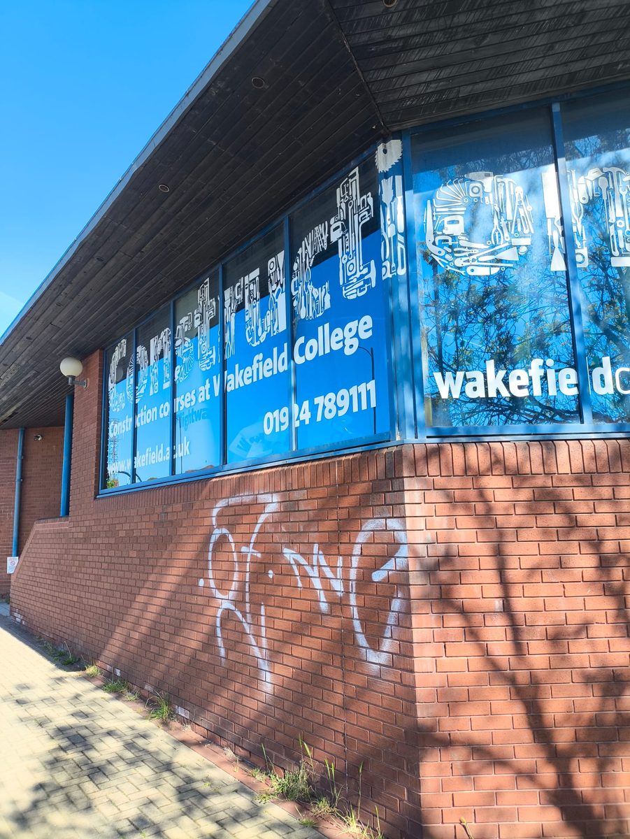 Graffiti on a commercial brick wall before laser cleaning