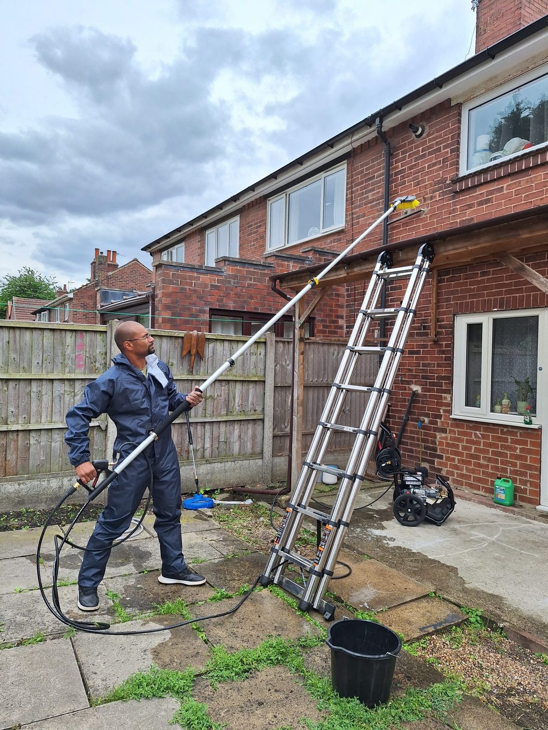 Technician cleaning house windows with a water-fed pole